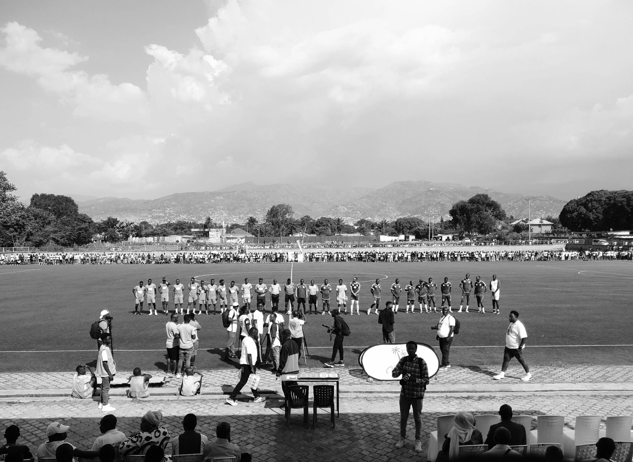 Players line up for a soccer match amid a scenic backdrop.